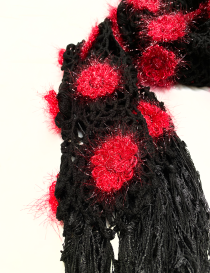 Detailed view of black tassels and red floral squares on a crochet scarf.