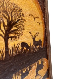 Detailed wood-burning of a stag and grazing deer against a golden sun.