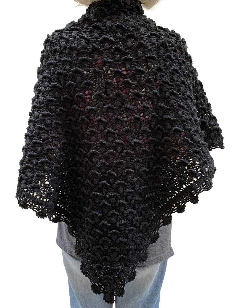 Rear view of a woman wearing a black triangular crochet wrap.