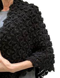 Close-up of black shimmery crochet shawl draped over shoulders.