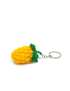 Close-up side view of a textured crochet pineapple fruit charm laying on a white surface.