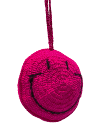 Closeup to handmade fuchsia pink crochet smiley face hanging decoration.