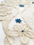 Close-up of the woven floral lace motifs and blue thread accents.