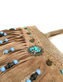Close-up of turquoise stones and bronze medallions on leather fringe.