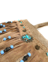 Close-up of turquoise stones and bronze medallions on leather fringe.