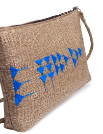 Close-up of blue hand-embroidered Phoenician script on natural jute fabric.