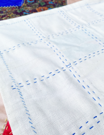 Raw linen backing with visible hand-stitched embroidery detail.