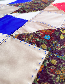 Close-up of mixed fabric textures and blue hand-stitching.