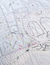 Reverse side showing intricate needlework and thread patterns of the textile art.