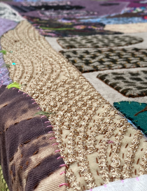 Angled view of gold thread embroidery and raised textile patterns.