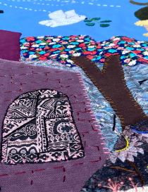 Detail of a white peace dove and olive branch embroidered on blue fabric.