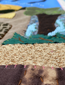 Macro view of textured gold embroidery and layered fabric appliqué stitching.