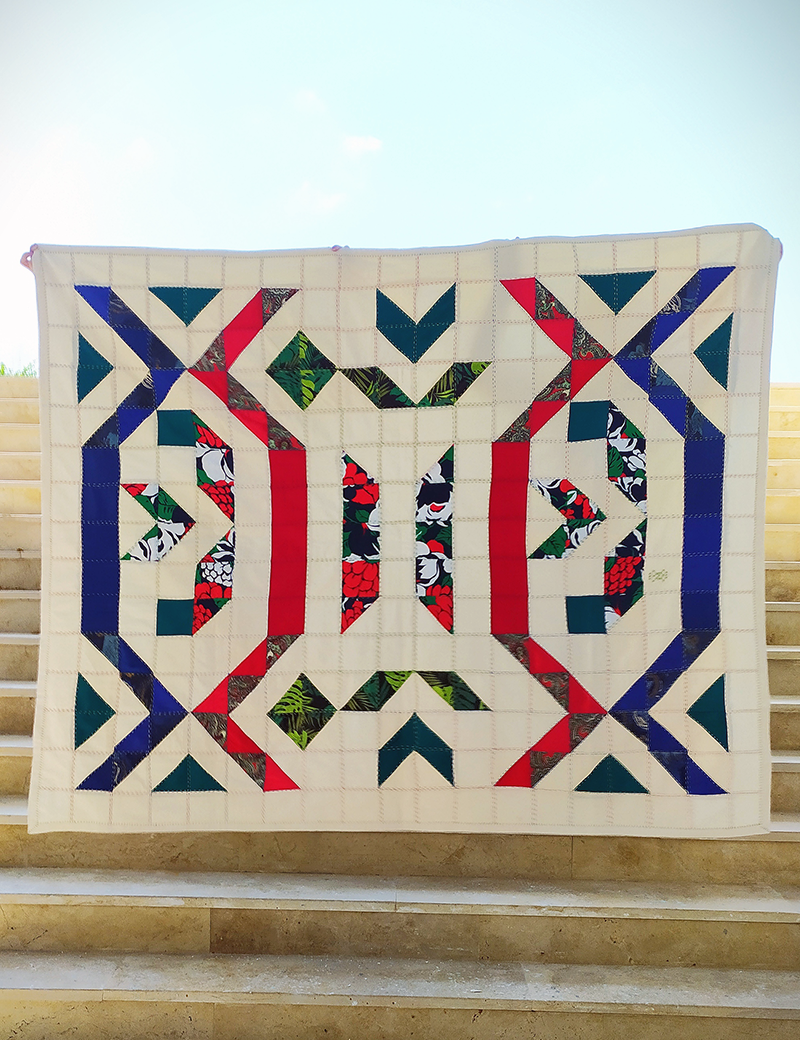 Full view of handmade Syrian geometric embroidered bedspread on white linen.