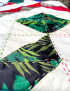Detail of green and black palm leaf embroidery on raw fabric base.