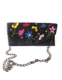 Close-up of vibrant hand-embroidered flowers on a black textured bag.