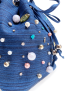 Detailed shot of hand-sewn beads and turquoise stones on denim fabric.