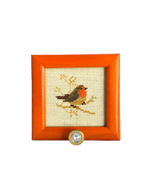Front view of a square orange wooden frame with bird cross-stitch and a crystal hook.
