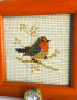 Close-up of the robin needlepoint embroidery and faceted glass knob detail.