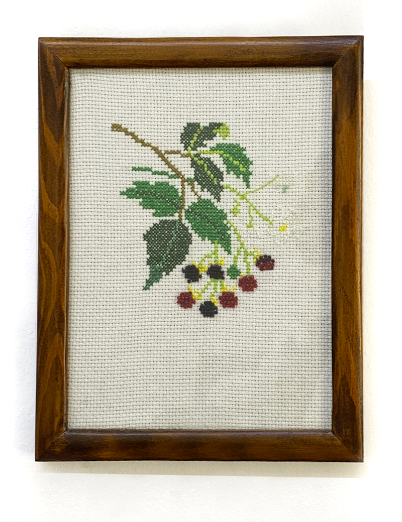 Front view of blackberry branch cross-stitch embroidery in wooden frame.
