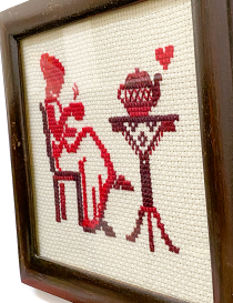Close-up of red embroidery stitches showing woman and teapot detail.
