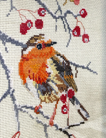 Close-up of handmade robin embroidery stitching details.