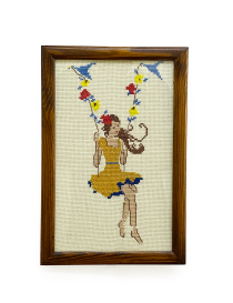 Framed handmade cross-stitch of girl on flower swing wall art.