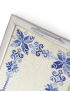 Close-up of blue cross-stitch embroidery and silver handle on wooden serving tray.