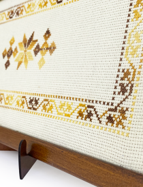 Detailed view of intricate cross-stitch embroidery and fabric texture on a decorative tray.