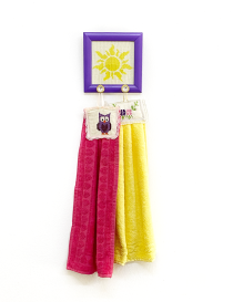 Set of embroidered towels displayed on a decorative sun-motif wall rack.