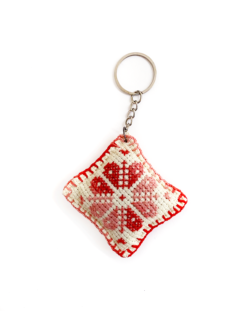 Traditional Syrian handmade cross-stitch keychain with red geometric pattern.
