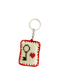 Front view of handmade cross-stitch keychain with black key and red heart embroidery on cream fabric.