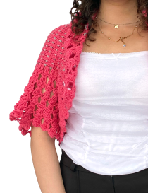 Model wearing Raspberry Bloom pink crochet shrug over a white top.