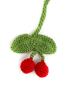 Detailed view of two red crochet cherries hanging from a green knitted stem and leaves.