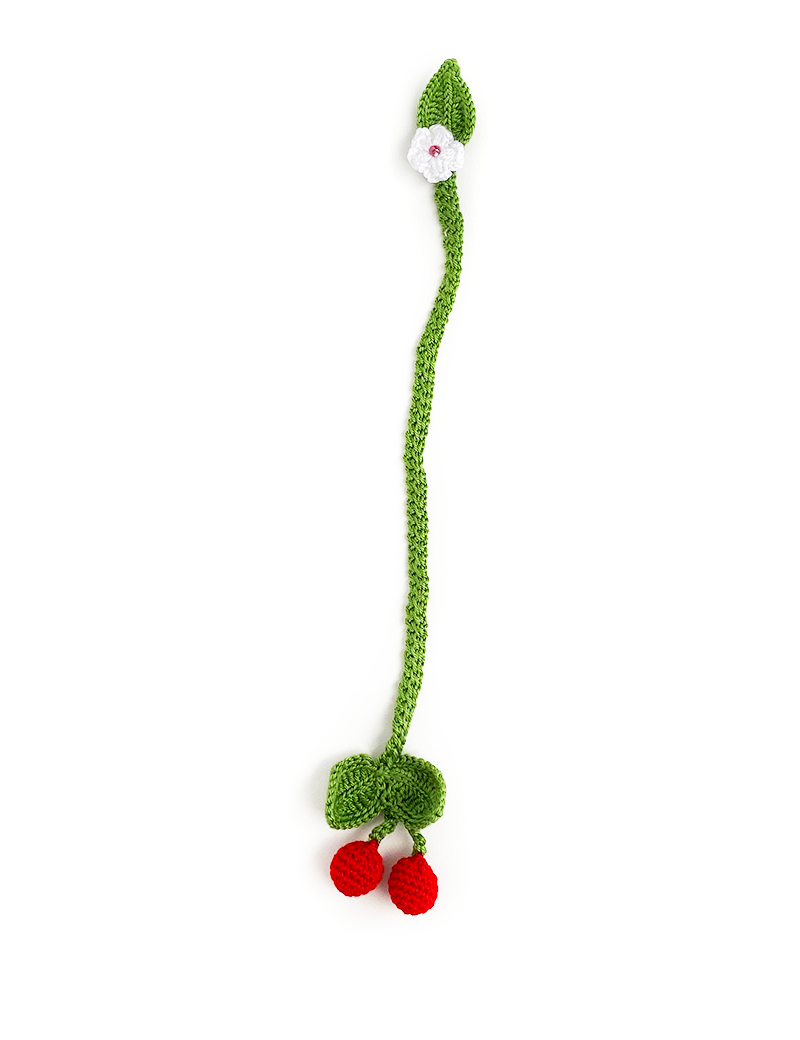 Full-length view of a green crochet bookmark with a white flower at the top and red cherries at the bottom.