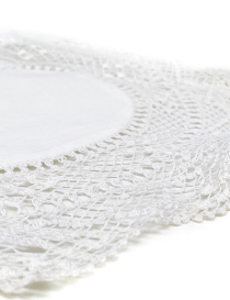 Close-up of intricate crochet lace patterns on a white handmade coaster.