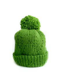 Close-up of green handmade crochet beanie with pom-pom and 3D leaf stitch.
