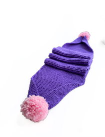 Long view of a mauve purple knitted scarf for women with fluffy pink pom pom ends.