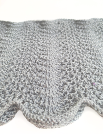 Close-up of Mufaragh stitch and silver Qasab sparkle on grey knit.