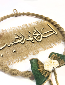 Detail shot of green burlap bow and cream fabric roses on wall decor.