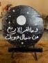 Black wooden round painted with moon, stars, and white Arabic script about beauty and eyes.