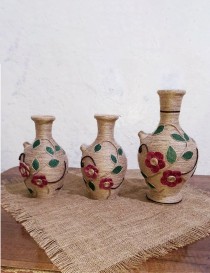 Handmade jute-wrapped clay vase with orange twine flowers and green leaves.