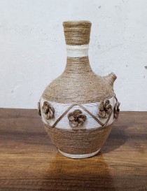 Handmade jute-wrapped clay vase with beige twine flowers.