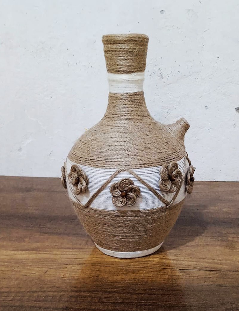 Handmade jute-wrapped clay vase with beige twine flowers.