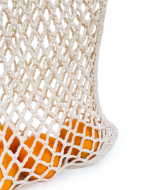 Beige cotton crochet net market bag with pink chevron handles containing oranges.