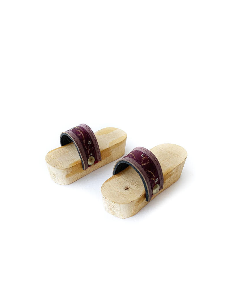 Top view of miniature wooden Qabqab shoes with burgundy embroidered straps.
