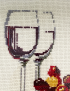 Detailed cross-stitch embroidery of wine glasses and grapes.