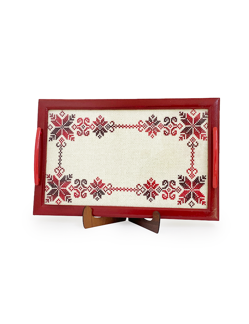 Frontal view of a rectangular serving tray featuring red snowflake cross-stitch patterns on a display stand.