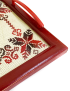 Close-up detail of red and black cross-stitch needlework and the polished burgundy wood frame.