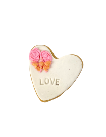 Heart-shaped sugar cookie with "LOVE" stamp and pink roses with gold bow.