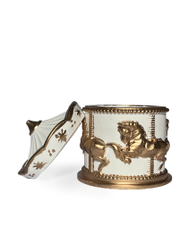 White and gold carousel candle with the lid leaning against the jar to show construction.